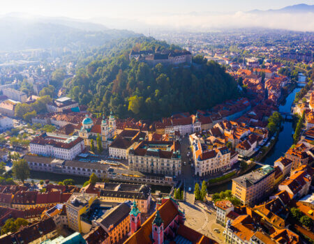 Panoramic aerial view of Ljubljana downtown with ancient castle complex on hilltop in sunny autumn morning, Slovenia